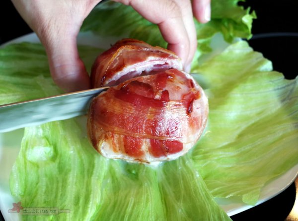 chiliblueten-mozzarella-mit-messer Schnitt durch mit Speck umwickelten Büffelmozzarella